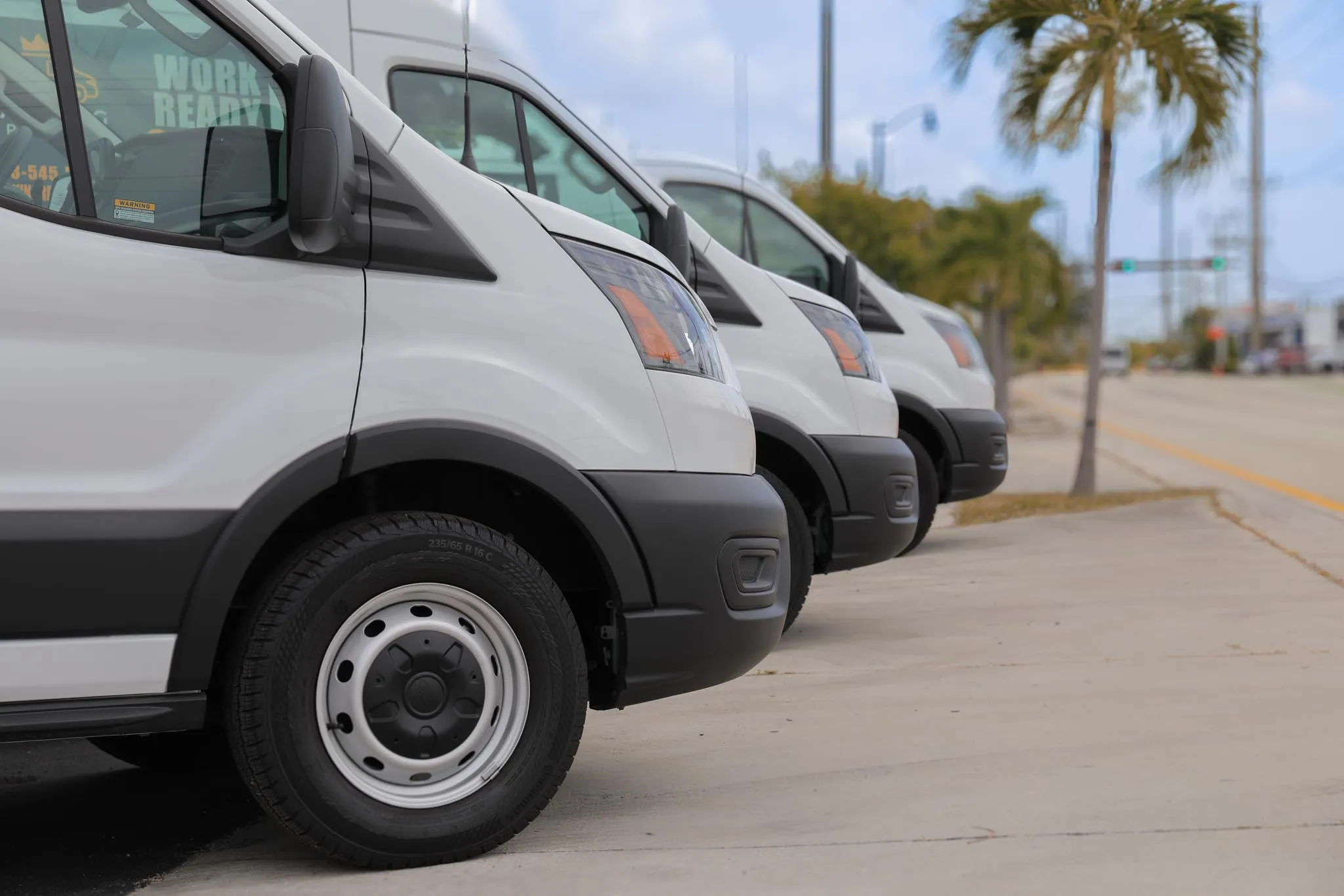 Mercedes-Benz Sprinter and Ford Transit cargo vans lined up at the VansKing Rentals lot in Pompano Beach, Florida
